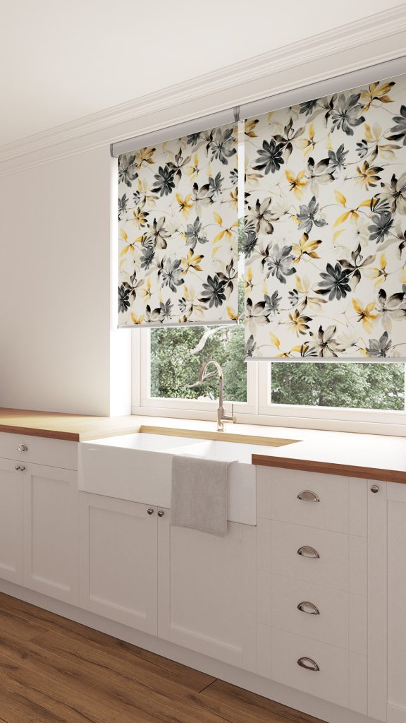 Roller blinds in a kitchen above the sink. The roller blinds are white with black and yellow flowers.